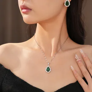 Close-up detail showing an emerald green teardrop necklace and matching earrings set