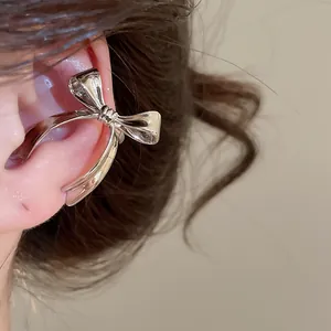Primer plano de un elegante ear cuff de lazo en plata pulida para orejas sin agujeros