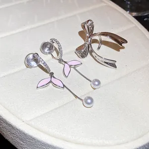 Vista detallada de pendientes de hoja rosa con perlas y un clip de oreja con lazo