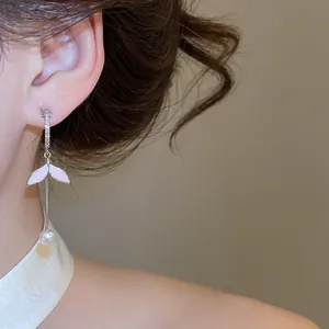 Vista detallada de los pendientes con forma de hoja rosa y perla blanca lucidos por una modelo