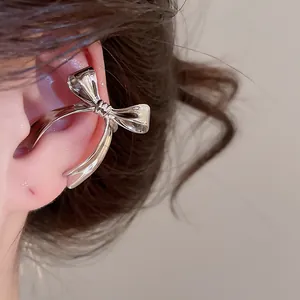 Earcuff de lazo plateado mostrado de cerca en una oreja femenina en detalle macro