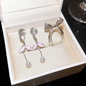 Vista detallada de pendientes de clip con perlas y hojas rosas y un anillo de lazo plateado