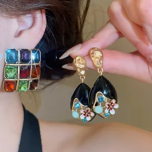 Close-up of vintage colorful gemstone square studs and floral teardrop earrings