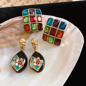 Detailed view of vintage black enamel flower earrings and colorful gemstone studs