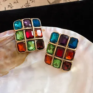 Detailed view of vintage square stud earrings with multi-colored gemstones on a pearl shell