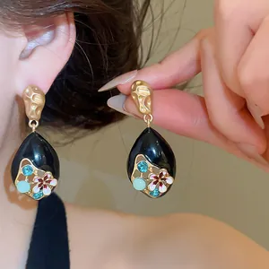 Macro view of teardrop enamel earrings with Monet-inspired floral and crystal details