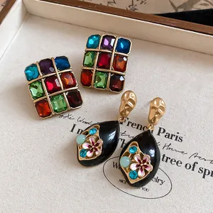 Close-up of vintage Monet-style colorful crystal square studs and black floral teardrop earrings.