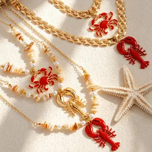 Detailed view of bohemian necklaces with red lobster and crab pendants on beach sand