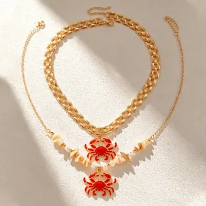Detail of red crab pendant necklaces with white shell beads and gold chain