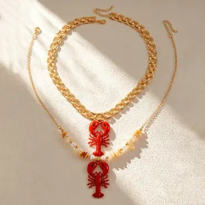 Detail of beach style necklaces featuring red lobster pendants with shells and faux pearls.