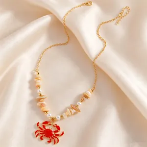 Detailed view of Bohemian gold necklace featuring red crab pendant and faux pearls