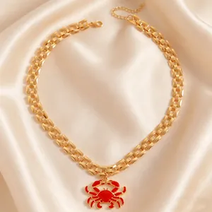 Close-up of gold-toned chunky chain necklace with a vibrant red crab pendant.