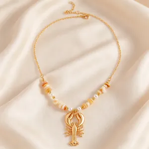 Macro detail of a bohemian gold lobster pendant necklace with pearls and white shell fragments