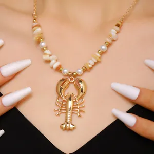 Close-up of a bohemian gold-toned lobster pendant necklace with shell beads and faux pearls.