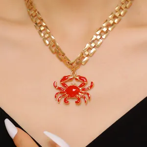 Close-up of a vibrant red enamel crab pendant on a chunky gold link chain
