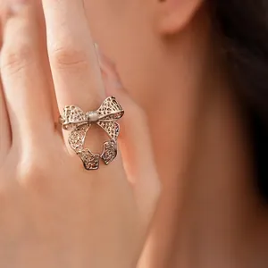 Elegant hollow bow-shaped open ring shown on model finger in a soft lifestyle setting