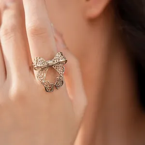 Detailed macro view of an elegant hollow metal bow-knot open ring worn on a finger