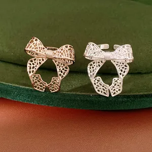 Detailed close-up view of elegant gold and silver hollow bow open rings on green velvet