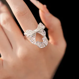 Detailed close-up of a delicate hollow-out silver bow open ring on a woman's finger