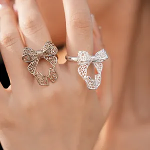 Intricate hollow bow-knot open adjustable rings in silver and gold finishes.