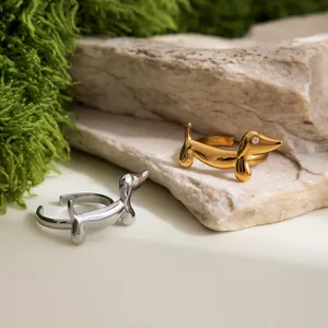 Dettaglio di anelli aperti in acciaio inox a forma di bassotto, color oro e argento.