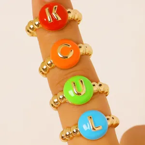 Primo piano di anelli colorati stile dopamina con lettere dorate K C U L sulle dita.