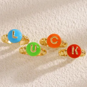 Set di quattro anelli dorati con perline e top in smalto colorato e lettere LUCK