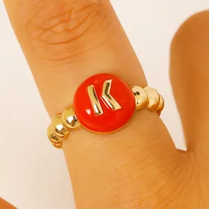 Primo piano di un anello a sfere dorate con iniziale K in smalto rosso da donna