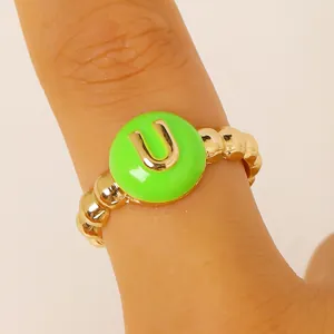 Dettaglio macro di un anello dorato con lettera U e smalto verde acceso al centro