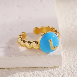 Dettaglio di un anello regolabile placcato oro con quadrante in smalto blu e lettera L dorata.