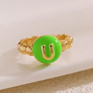 Primo piano di un anello a sfere dorato con smalto verde e la lettera dorata U