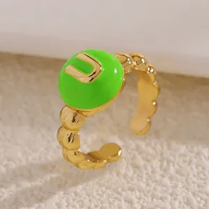Dettaglio macro di anello dorato con smalto verde neon e lettera U in rilievo