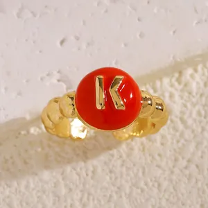 Vista dettagliata di un anello dorato regolabile con smalto rosso e la lettera K d'oro
