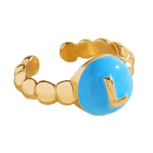 Vista dettagliata di un anello dorato aperto con inserto in smalto blu e lettera L