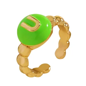 Dettaglio ravvicinato di un anello in smalto verde con lettera iniziale U dorata.