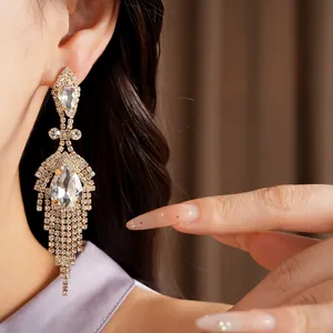 Gros plan détaillé de boucles d'oreilles à pompons en cristal portées par un modèle.