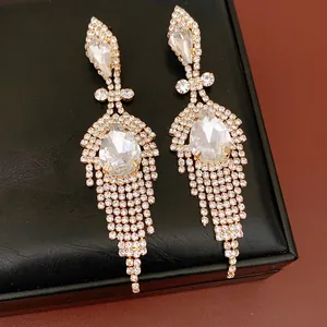 Gros plan détaillé de boucles d'oreilles en argent avec cristaux en goutte et glands.