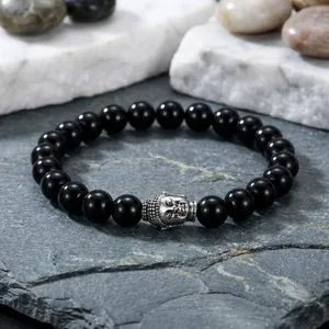 Macro shot of 10mm black round beads bracelet featuring a silver Buddha head charm