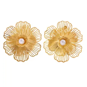 Detailed view of oversized golden hollow flower earrings with a central white faux pearl accent