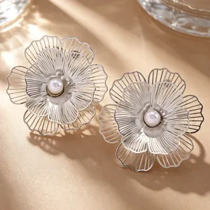 Detailed close-up view of silver filigree flower stud earrings with center white pearl