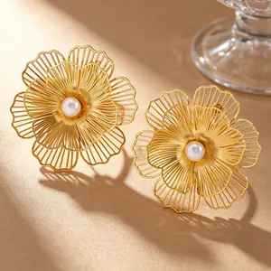 Macro detail of golden wireframe flower jewelry with central white faux pearl