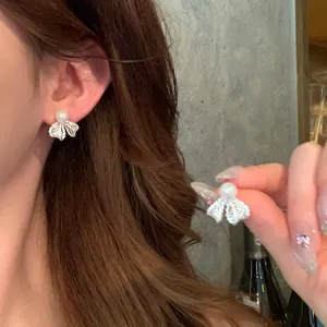Close-up of elegant bow-knot pearl earrings showing the delicate lace detail
