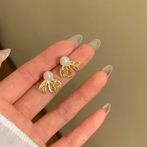 Detailed close-up showing the elegant 18K gold plated bow stud earrings with a white pearl