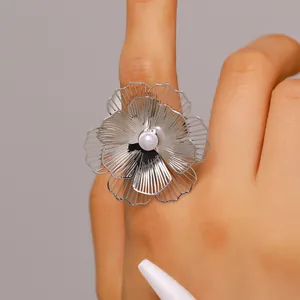 Close-up view of an oversized silver metal flower ring with a central white faux pearl detail