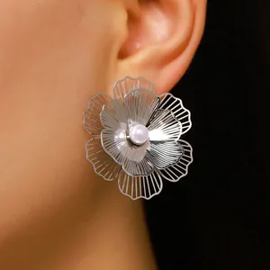 Detail shot of oversized silver floral stud earring featuring a white faux pearl center