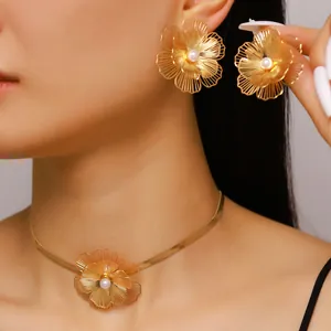 Macro view of oversized gold wire flower earrings and necklace with faux pearl centers