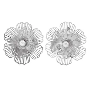 Detailed macro view showing silver flower stud earrings with a faux pearl center