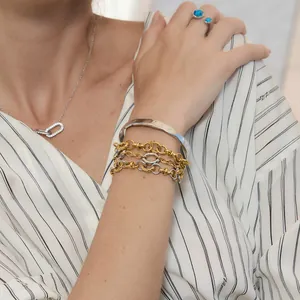 Vista detallada de pulseras de cadena de oro y plata con brazalete minimalista