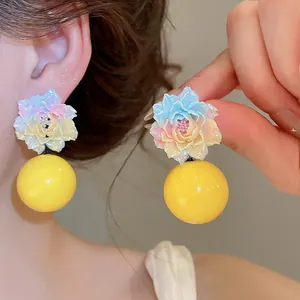 Detailed view of sweet resin flower earrings with yellow spherical drop pendants.