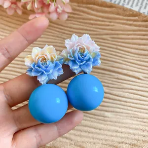 Close-up of vibrant blue resin flower earrings with matching spherical beads